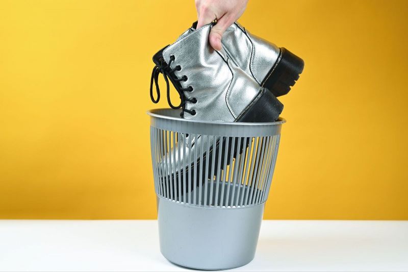 Fashion boots symbolically being thrown in trash