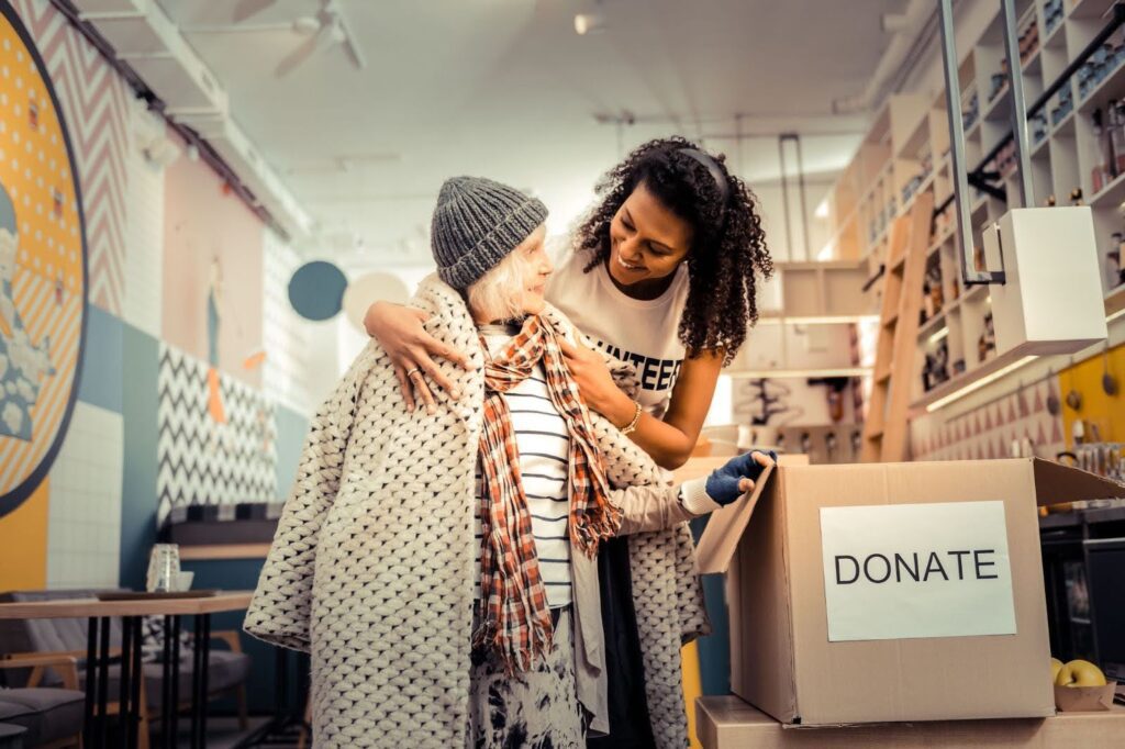 oyful volunteer donating coat to underprivileged woman