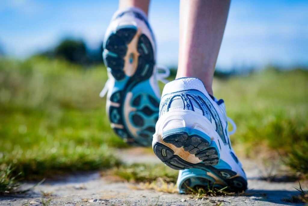 Person wearing running shoes on outdoor trail for health and well-being